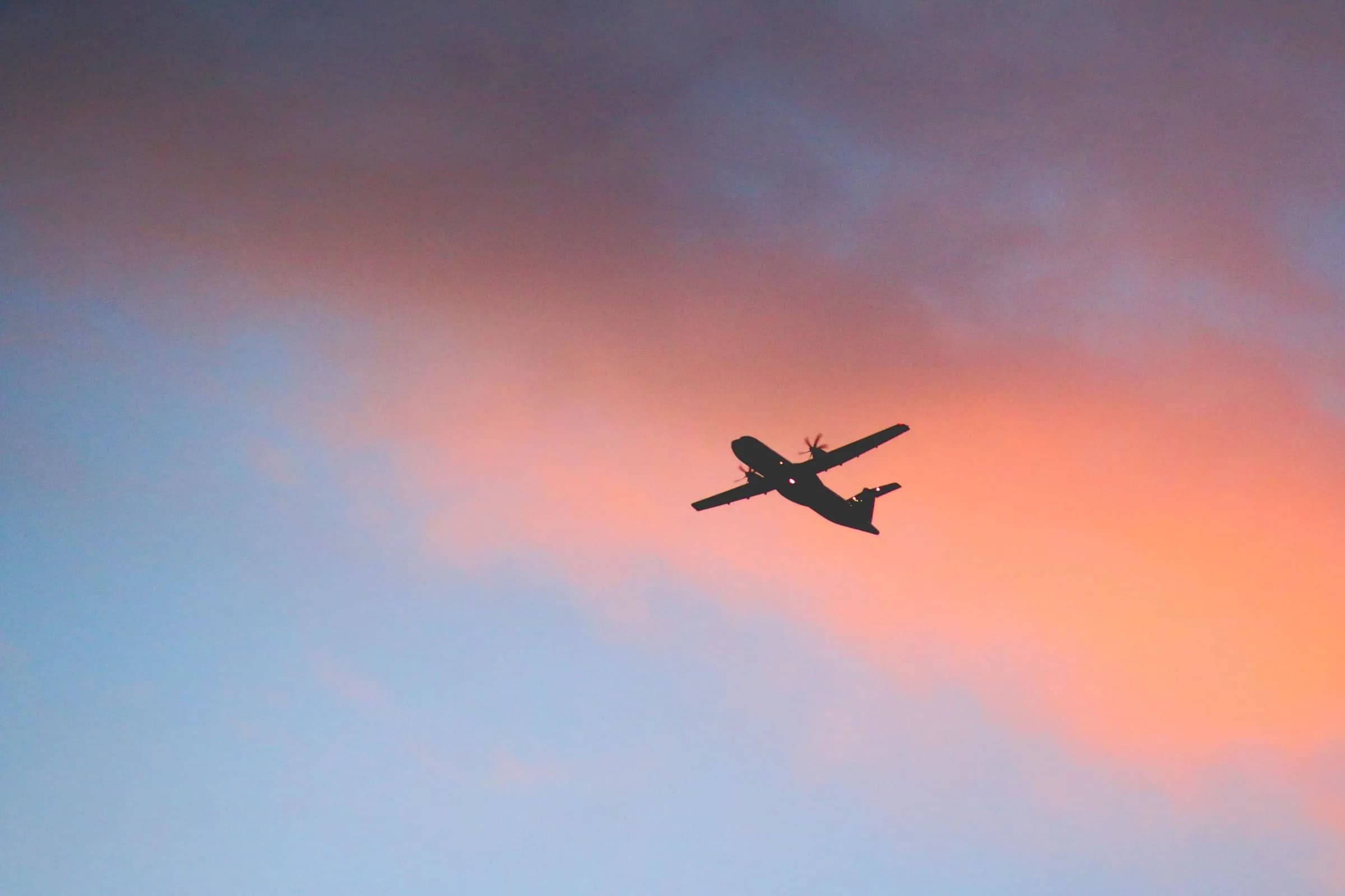 An airplane flying through a sunset sky